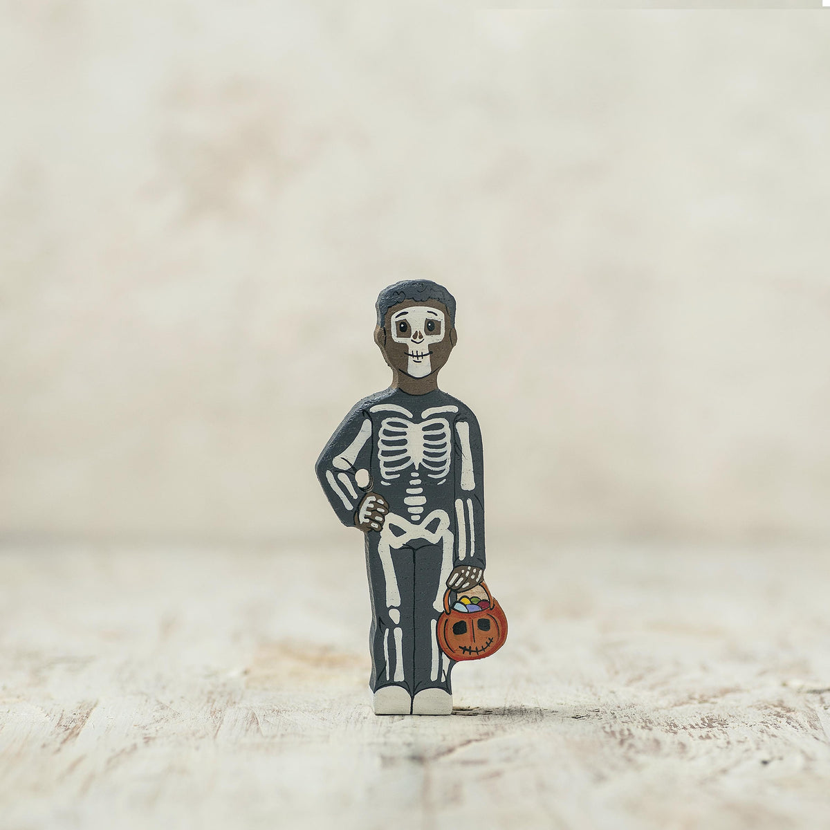 Wooden skeleton child holding a pumpkin candy basket