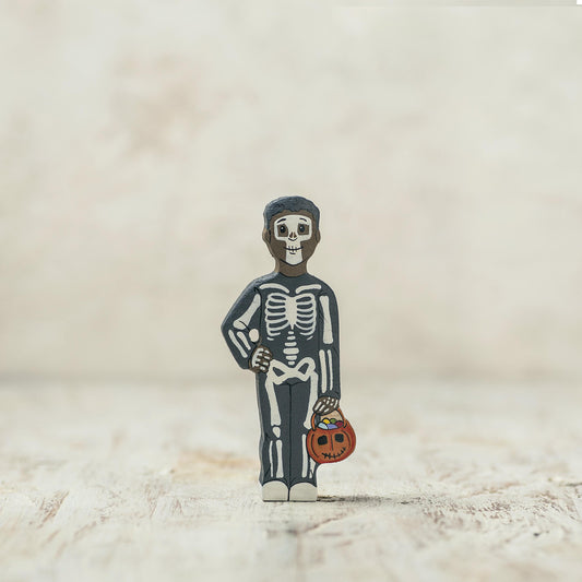 Wooden skeleton child holding a pumpkin candy basket